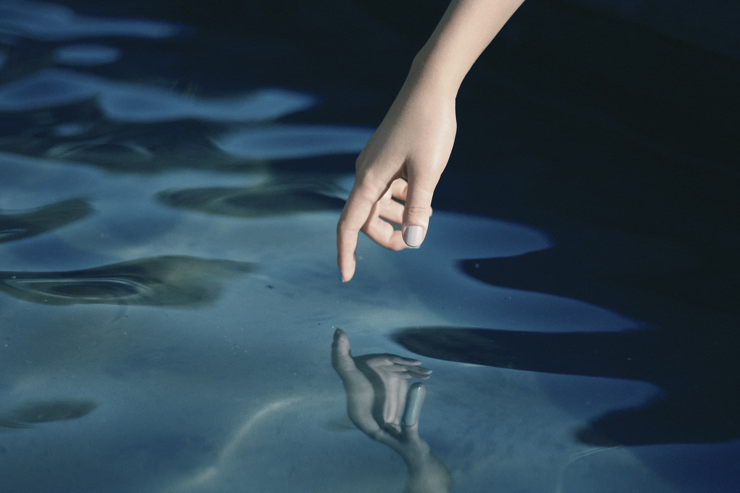 A fingertip resting on still water